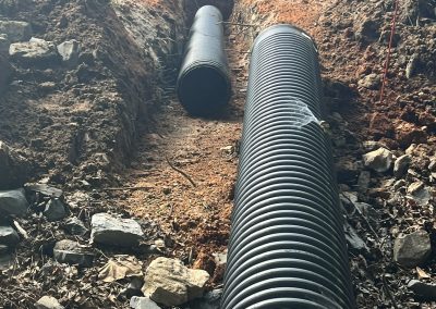 Culvert pipe being set in a drainage trench during driveway installation