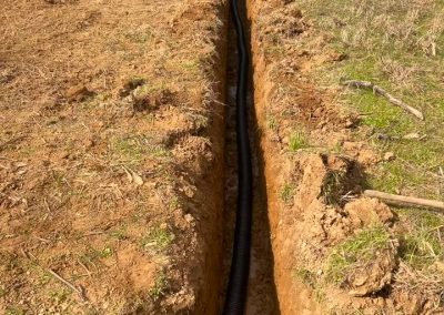 Drain tile installation with perforated pipe and gravel bed for yard drainage