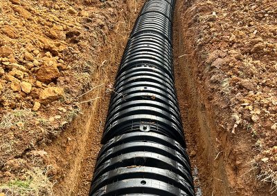 Drain field trenching with perforated pipe and gravel base for a septic system