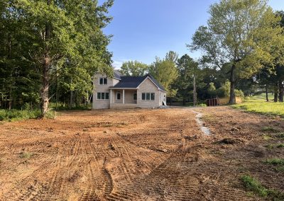 Curtain drain trench with gravel and pipe installed to intercept groundwater on a sloped yard