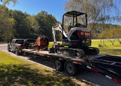 Excavator installing underground utility line trench at sunset